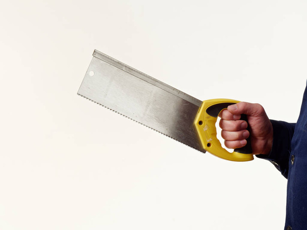 ο άνθρωπος σε ρουχισμός εργασίας είναι εκμετάλλευση ένα handsaw εργαλείο σε άσπρο φόντο 5 - Φωτογραφία, εικόνα