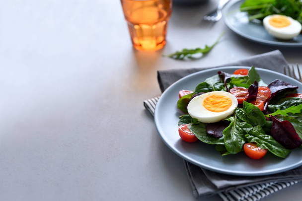 Salad mix with spinach, arugula,beet leaves, tomatoes and eggs on gray wooden background. Vegetarian food concept. Selective focus. - Φωτογραφία, εικόνα