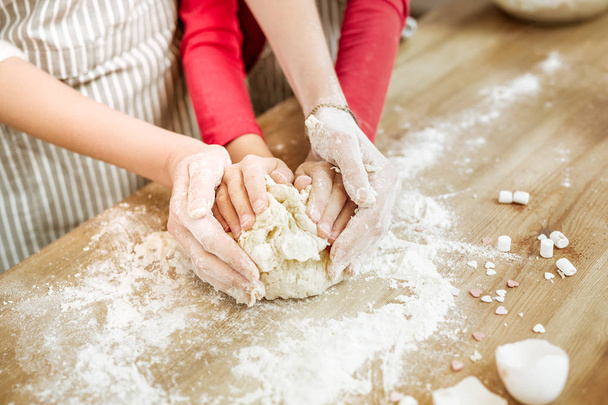 Little interested child gently hugging piece of unready dough - 写真・画像