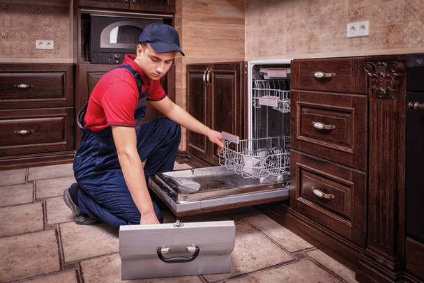 Joven técnico masculino Reparación de lavavajillas en la cocina
 - Foto, imagen