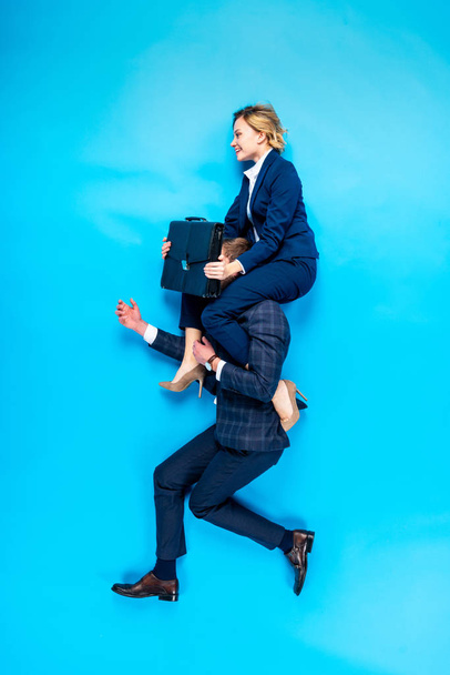Man in suit holding woman with briefcase on shoulders on blue background - 写真・画像