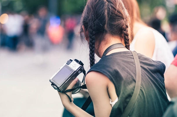 Asian girl learning to use a mirrorless camera with her mom in the public park. Selective focus on hand. - 写真・画像
