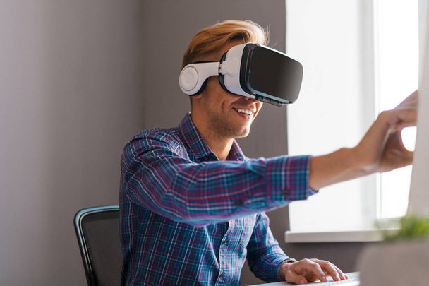 Smiling male in VR glasses using computer - Foto, immagini