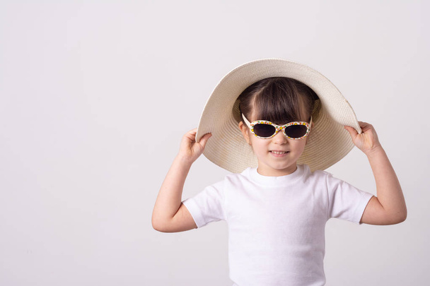 Vrolijk meisje in zonnebril, geïsoleerd op een witte achtergrond. Lachende schattige jongen in hoed.  - Foto, afbeelding