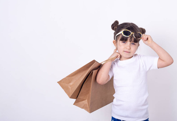 Les enfants achètent des achats. Petite fille portant des lunettes de soleil sur le shopping
.  - Photo, image