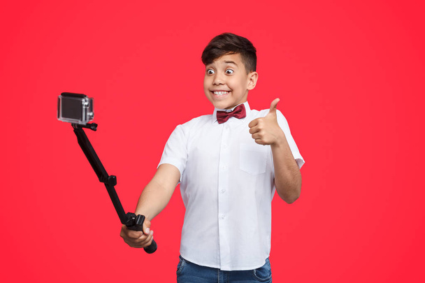 Excited boy gesturing thumb up and taking selfie - Foto, immagini