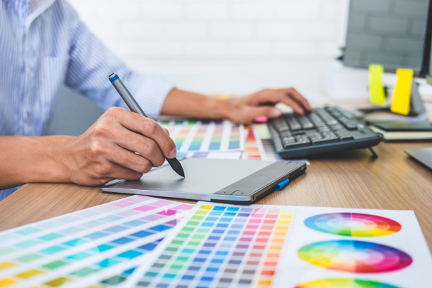 İş yerindeki iş araçları ve aksesuarlarla renk seçimi ve grafik tableti üzerinde çalışan erkek yaratıcı grafik tasarımcısının resmi. - Fotoğraf, Görsel