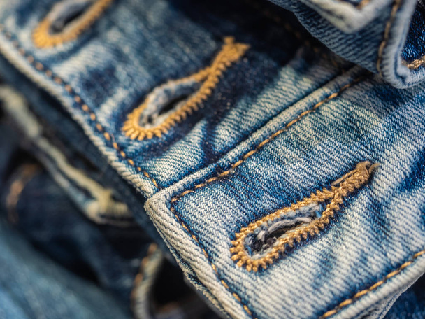 Levendig blauw dicht beeld van de tailleband van denim jeans met dubbele stiksels en metalen tack-knop - Foto, afbeelding