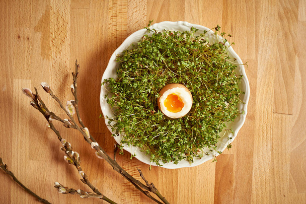 Βιολογικό κοτόπουλο βρασμένο αυγό στο πιάτο με τα λάχανα Κάρδαμο ξύλινο τραπέζι - Φωτογραφία, εικόνα