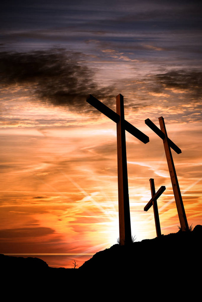 Silhueta de três cruzes de madeira acima da colina com céu dramático e raios de sol ao pôr do sol. Símbolo religioso de boa sexta-feira
 - Foto, Imagem
