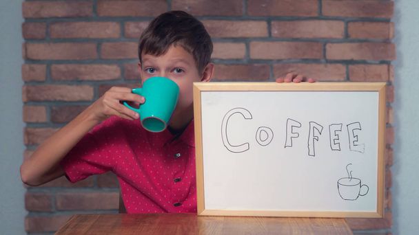 niño sentado en el escritorio sosteniendo el rotafolio con letras café
 - Foto, Imagen
