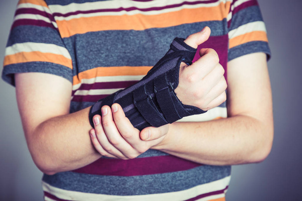 Man with hand in orthopedic black orthosis - Foto, imagen