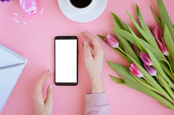 Styled feminine flatlay with pink tulip flowers, notebook, cup of coffee and smart phone - Foto, imagen