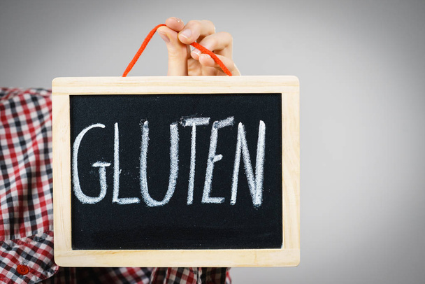 Woman holding small black board with gluten sign. Bakery and bread allergy problem. - Фото, зображення
