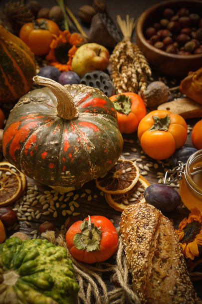 Pumpkins, persimmon, cereals, bread, seeds and nuts on a wooden background, Harvest - 写真・画像