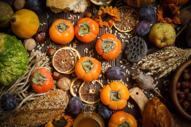 Pumpkins, persimmon, cereals, bread, seeds and nuts on a wooden background, Harvest - Fotografie, Obrázek