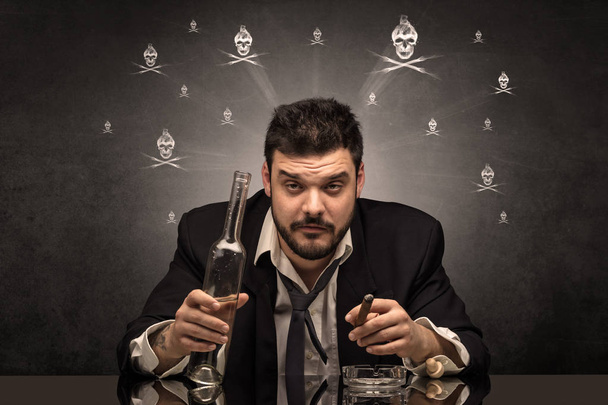 Drunk man sitting at table with skulls concept - Photo, Image