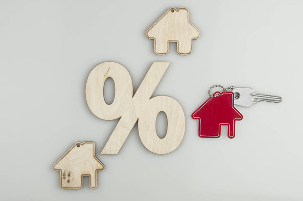 Концепция переселения и поиска жилья. Модель деревянного дома со знаком процента на белом фоне. Вид сверху
 - Фото, изображение