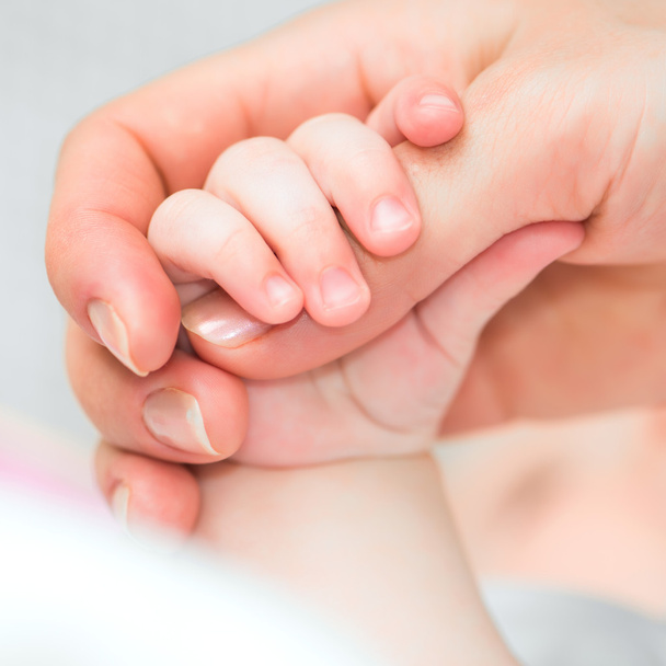 baby holds mother's finger - Foto, afbeelding