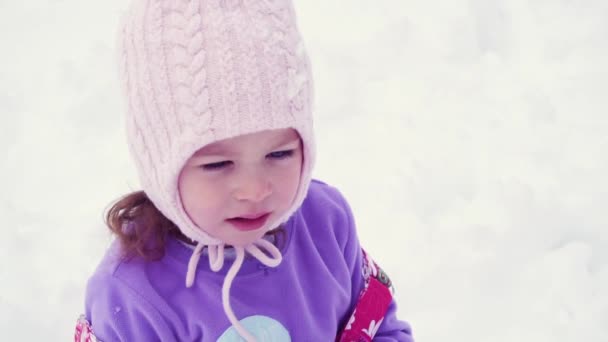 Slow motion. Little girl in pink hat playing in snow. - Felvétel, videó