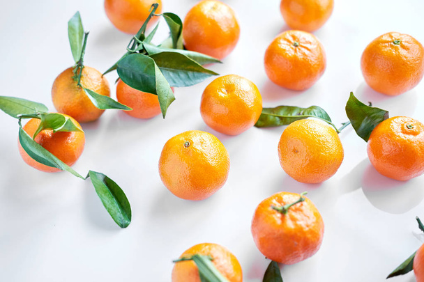 Skupina pomerančové čerstvé mandarinky s zelenými listy leží na bílém pozadí. Closeup.  - Fotografie, Obrázek