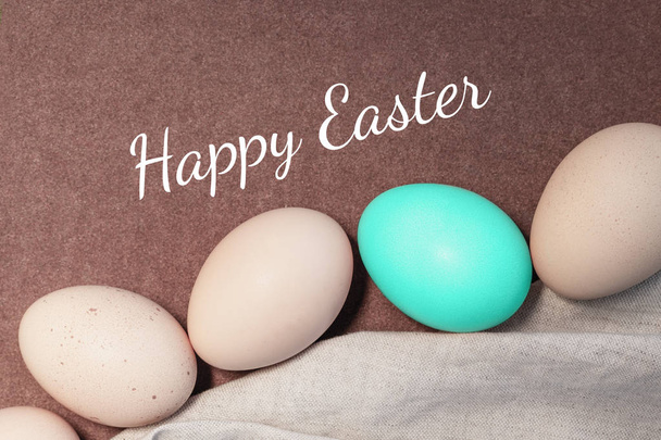 Easter eggs in natural and blue color on a brown background with the inscription Happy Easter - Foto, Imagem