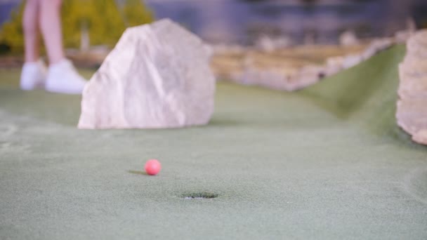 Egy fiatal nő, játék mini golf. Egy nő, ütő a sorban, és hiányzik néhány golflabda - Felvétel, videó