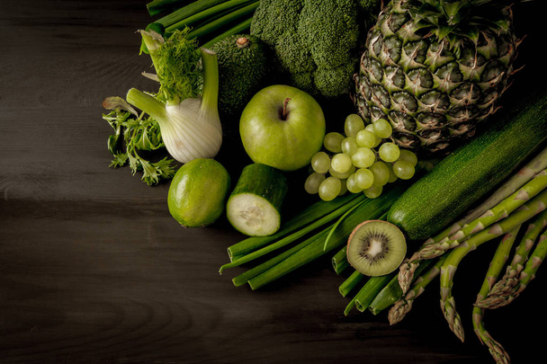 Green health smoothie fruits and vegetables, kale leaves, lime, apple, kiwi, grapes, banana, avocado, lettuce pineapple salat. Copy space. Raw, vegan, vegetarian, alkaline food concept. - Photo, Image