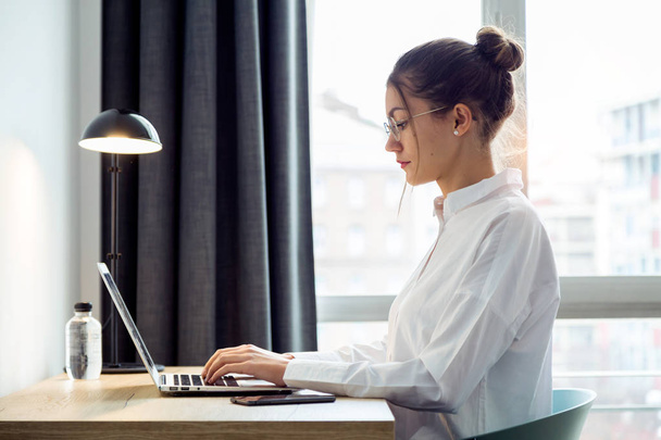 Shot of concentrated beautiful businesswoman working with her laptop on the desk at the hotel room. - Photo, image