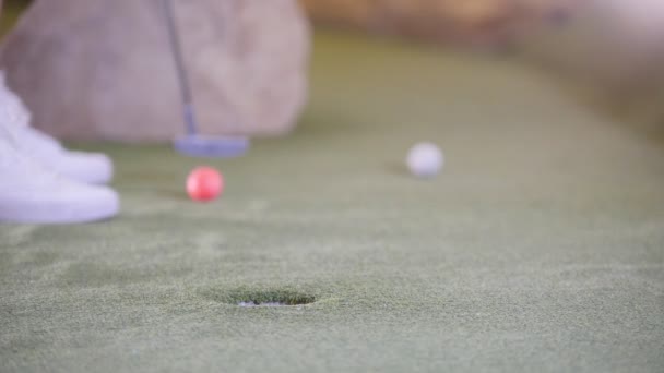 Játék mini golf. Az a személy, üti a golflabda és hiányzik. Közelről - Felvétel, videó