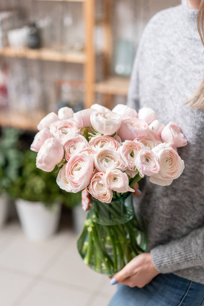 女性の手でガラスの花瓶のペルシャ キンポウゲ。淡いピンク色を束します。フラワー ショップ花屋のコンセプトです。壁紙。冬の季節の花 - 写真・画像