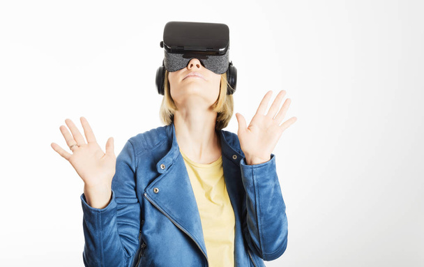 eine junge Frau trägt eine Virtual-Reality-Brille und greift mit den Händen nach etwas - Foto, Bild
