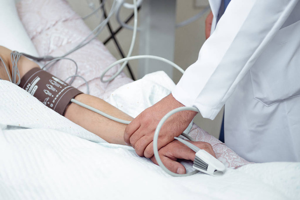Лікар вимірює пульс пацієнта зі спеціальним обладнанням у лікарні
 - Фото, зображення