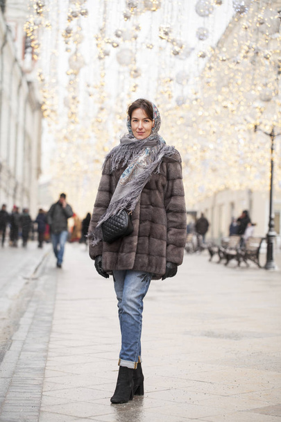 Happy Beautiful brunette woman in fur mink coat and scarf in the center of the Christmas courtyard - Foto, Imagen