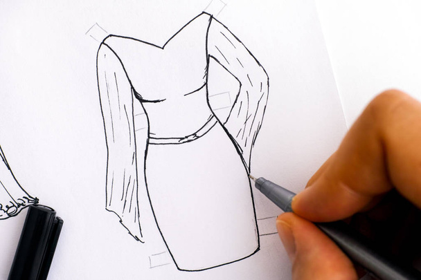 Женская рука с черным ручкой рисунок платье для бумажной куклы
. - Фото, изображение