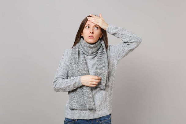 Worried woman in gray sweater, scarf put hand on forehead, looking up having headache isolated on grey background. Healthy lifestyle ill sick disease treatment cold season concept. Mock up copy space - Photo, Image