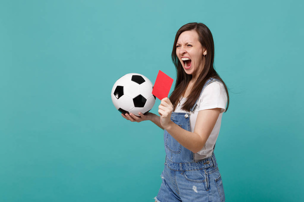 Ουρλιάζοντας τρελό νεαρή γυναίκα ποδόσφαιρο ανεμιστήρα ομάδα υποστήριξης με μπάλα ποδοσφαίρου, κόκκινη κάρτα, προτείνει παίκτης αποσυρθεί από πεδίο που απομονώνονται σε μπλε φόντο τιρκουάζ. Άνθρωποι συναισθήματα, έννοια του αθλητισμού αναψυχής από την οικογένεια - Φωτογραφία, εικόνα