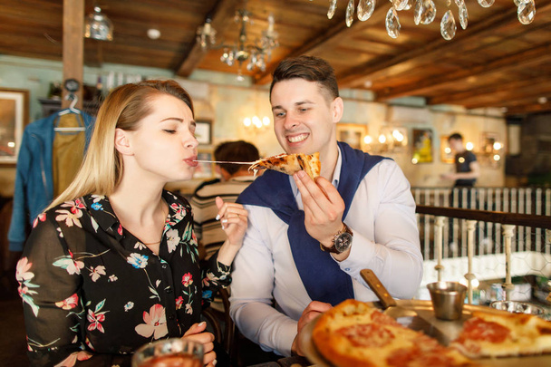 young beautiful couple eating pizza in a restaurant - Foto, Imagen