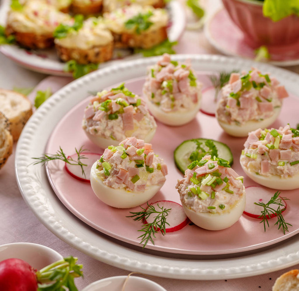 Deviled eggs, stuffed eggs filled with a paste made from smoked ham, mayonnaise, egg yolks and fresh chive on a plate.Tasty breakfast, appetizer for party or easter meals - Photo, Image