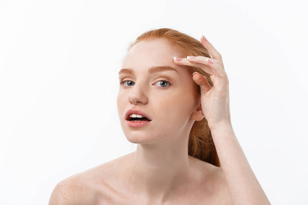 redheaded woman shows fingers on acne on her face. - 写真・画像