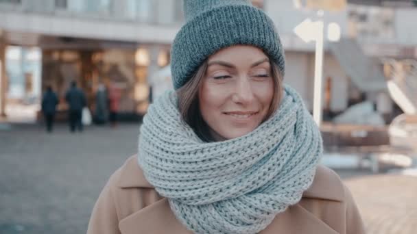 Portrait of gorgeous young woman in knit cap outdoor. Attractive young lady is smilig on city street - Footage, Video