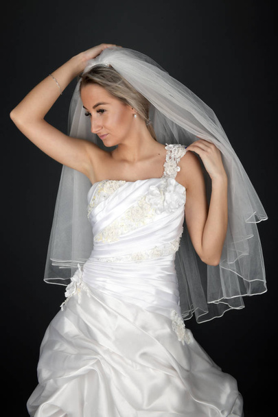 Beautiful blonde bride in a white dress on a black background - Fotografie, Obrázek