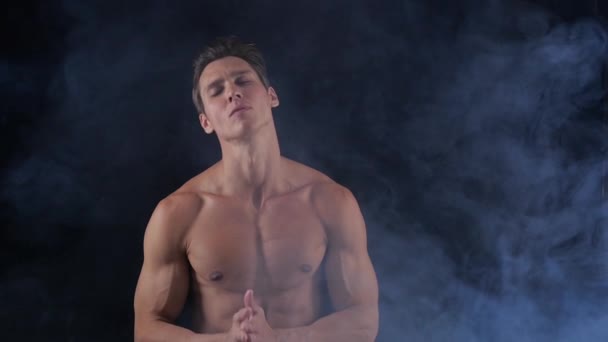 Όμορφος shirtless άνδρας στέκεται σε σκούρο φόντο, με καπνό γύρω από τον. - Πλάνα, βίντεο