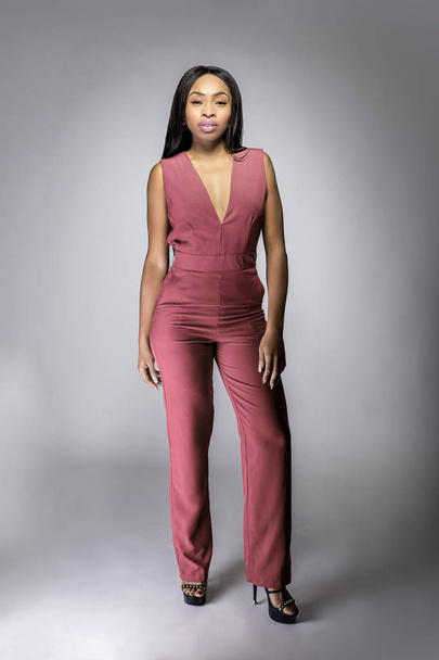 Black African-American female fashion model wearing the 2019 color of the year Pantone Living Coral on a v neck outfit.  The image depicts modern fashion design and style. - Foto, imagen