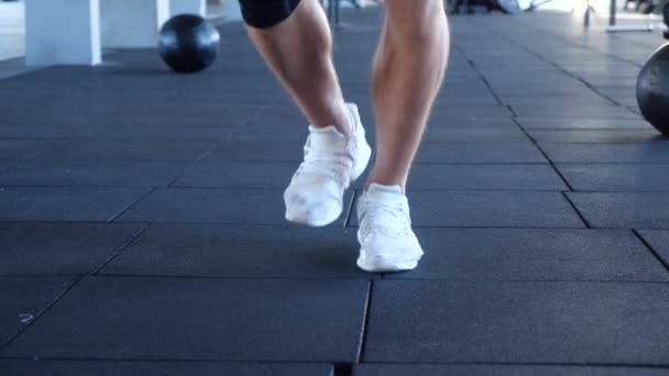 Close up Footwork of young athletic male jumping while practicing with a jump rope. Athletic male working out with a skipping rope at gym - Footage, Video