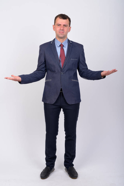 Полный снимок серьезного бизнесмена в костюме пожимающего плечами
 - Фото, изображение