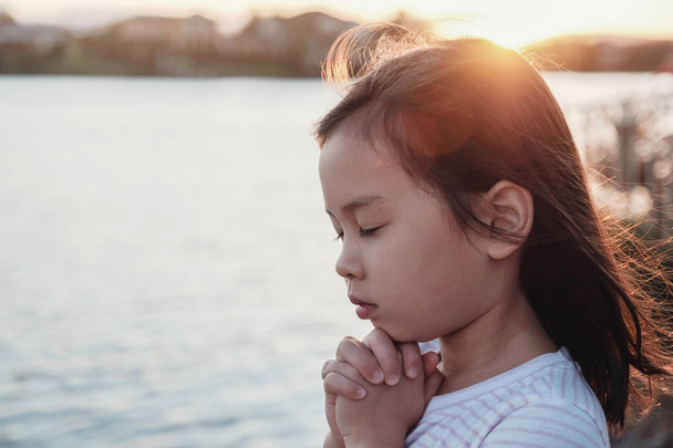 Niña multicultural rezando con fondo de sol - Foto, Imagen