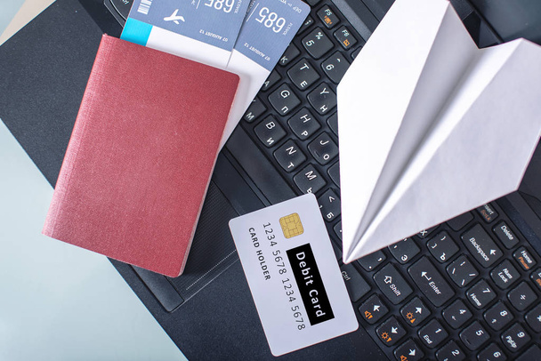 Vliegtickets, paspoort, debetkaart en papieren vliegtuig staan op het toetsenbord van de laptop. Het concept van online kopen en boeken - Foto, afbeelding