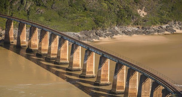 Vanha rautatiesilta ylittää leveän joen Etelä-Afrikassa. Se on yksiraiteinen ja sitä tukee betonipylväiden rakentaminen
. - Valokuva, kuva