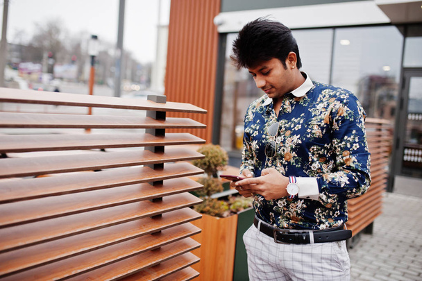 Attractive and handsome stylish indian man wear on shirt, holding mobile phone and standing in the terrace of modern lounge cafe at his work break. - Photo, Image